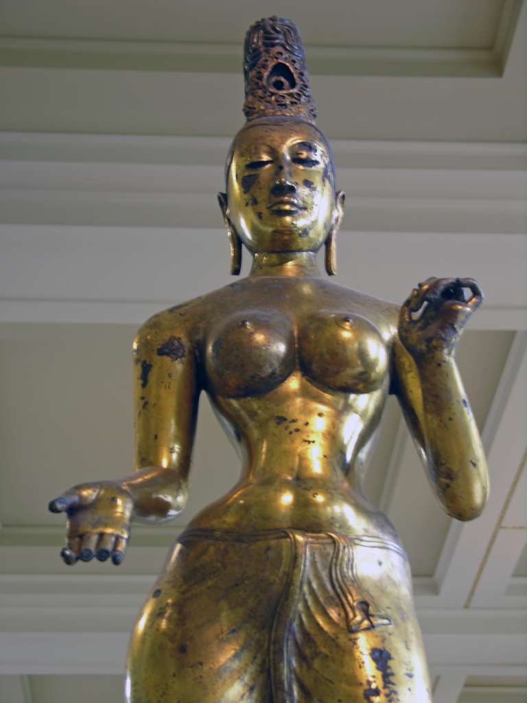 British Museum Top 20 06 Gilded Bronze Tara 6. Standing Tara � Sri Lanka, 8C AD, 143cm high. The statue of Tara, the consort of Avalokiteshvara, is solid cast in one piece of bronze and gilded. The goddess is naked to the waist with a lower garment flowing to her ankles. The marked contrast of the slender waist against heavy breasts and hips is the ideal of feminine beauty. Tara's right hand is shown in the mudra of giving; her left hand is empty but may have held a lotus flower.
